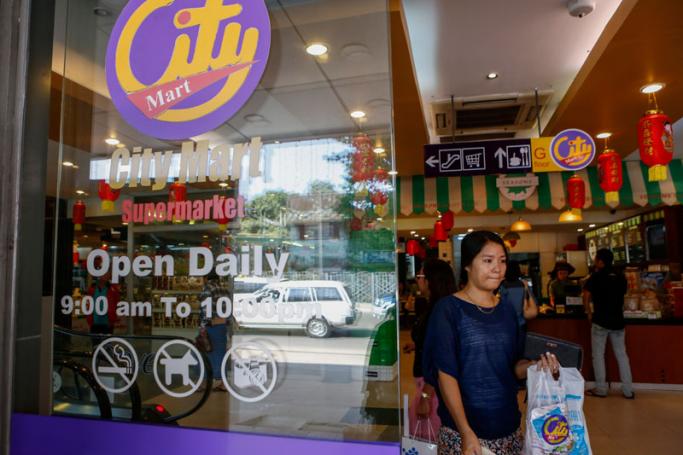 A customer comes out from City Mart supermarket after shopping in Yangon, Myanmar, 12 January 2016. Photo: Lynn Bo Bo/EPA
