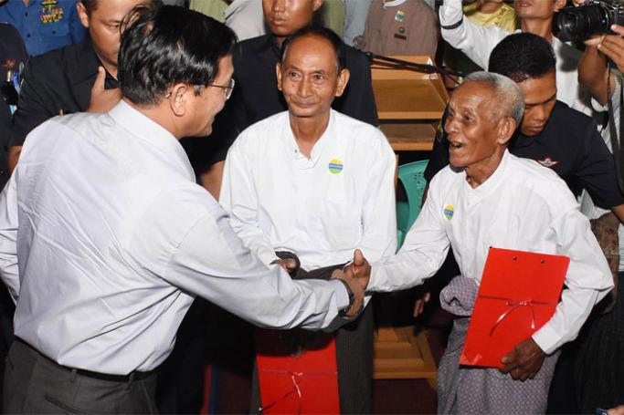 Vice President U Henry Van Thio, left, shakes hands with a farmer at a ceremony yesterday to return confiscated farmland to farmers in Myittha, Mandalay Region. Photo: MNA
