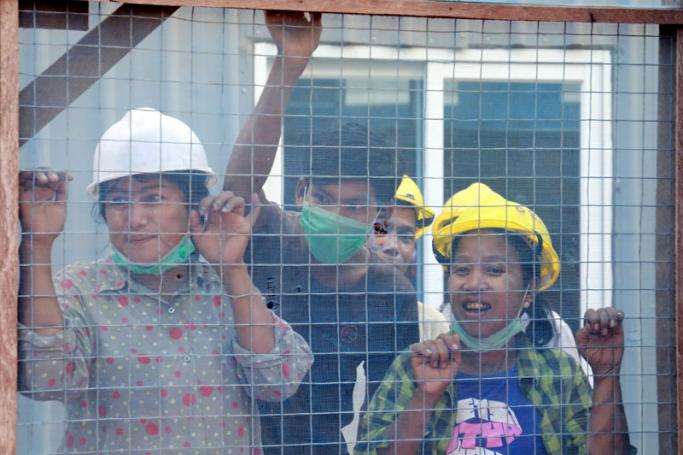 Construction workers look out from the construction site during the Car Free Bank Street Fair in Yangon. Photo: Nyein Chan Naing/EPA-EFE
