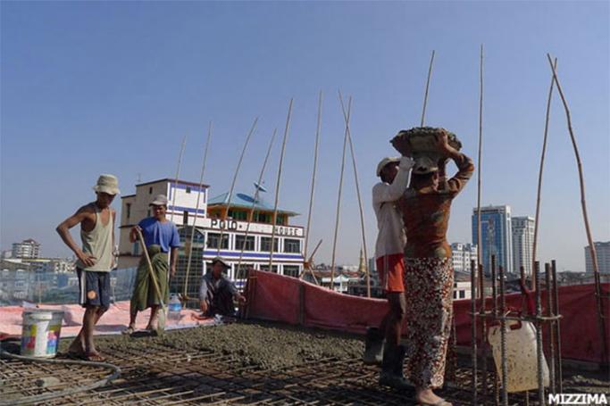 Construction workers pour cement on the roof of a new commercial high rise building in Yangon. Photo: Mizzima
