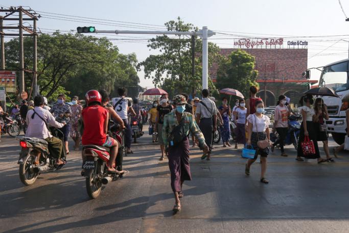 Commuters wearing face masks amid concerns over the spread of the COVID-19 coronavirus make their way by walking and by bikes in the Hlaing Tharyar township on the outskirts of Yangon on May 16, 2020. Photo: Sai Aung Main/AFP
