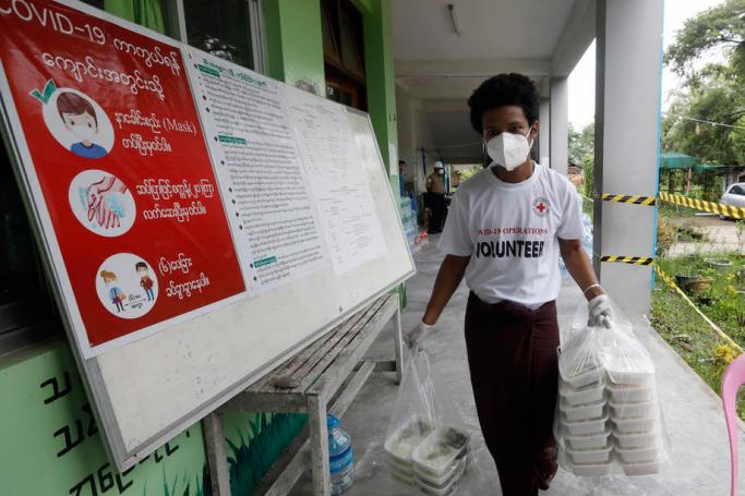  A Red Cross volunteer carries lunch boxes for the people at a quarantine facility center in Yangon. Photo: Nyein Chan Naing/EPA
