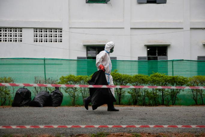 A man wearing PPE (personal protective equipment) carries garbage bags in front of a quarantine dormitory at a community quarantine center facilitated by the Myanmar military, in Yangon, Myanmar, 20 May 2020. Photo: Lynn Bo Bo/EPA