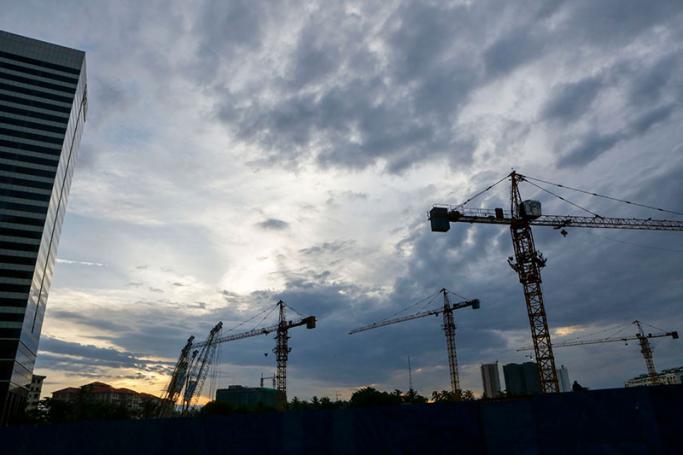 Cranes from construction and a high building lie under clouds at early morning in Yangon. Photo: Lynn Bo Bo/EPA
