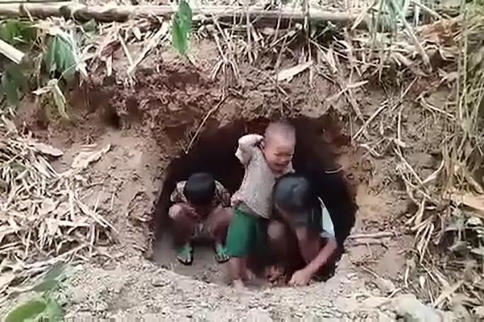 This screengrab from a UGC video provided to AFPTV from an anonymous source taken on April 4, 2021 shows young displaced children sheltering in holes dug in the forest in Myanmar's Pupun district near the border with Thailand. Photo: AFP