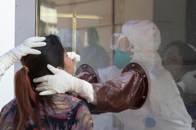 Medical workers wearing PPE (Personal protective equipment) take swab samples from a woman during the coronavirus disease (COVID-19) rapid diagnostic testing for domestic air travel at downtown area in Yangon, Myanmar, 15 December 2020. Photo: Lynn Bo Bo/EPA
