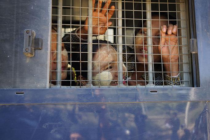 Detained farmers look out from the window of a prison van upon their arrival at a courthouse in Sintgaing in Mandalay region on January 10, 2017. Photo: Kyaw Zay Win/AFP
