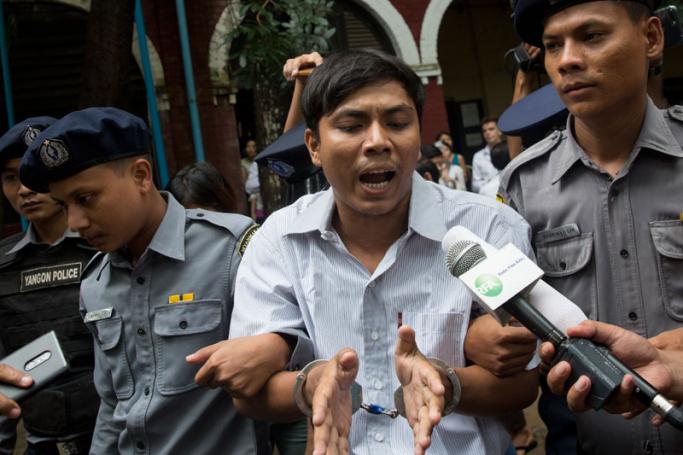 Detained Reuters journalist Kyaw Soe Oo (C) talks to media while being escorted by police as he leaves the court after his trial hearing in Yangon, Myanmar, 02 July 2018. Photo: Lynn Bo Bo/EPA-EFE
