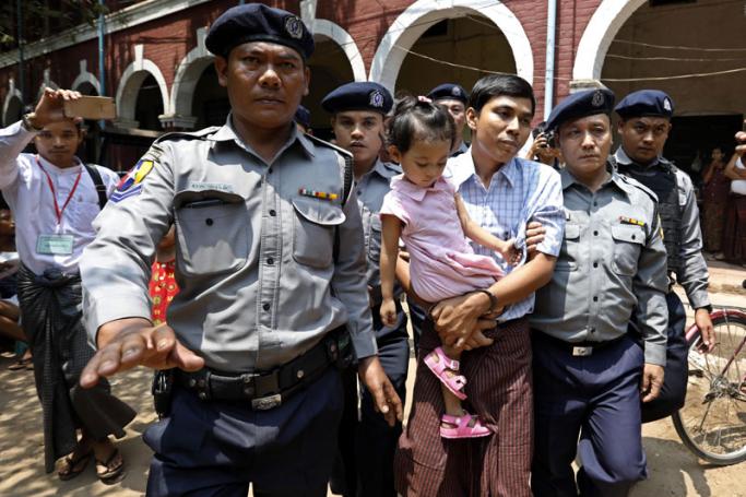 Detained Reuters journalist Kyaw Soe Oo (C) is escorted by police as he holds his daughter during a break in the trial at the court in Yangon, Myanmar, 28 March 2018. Photo: Nyein Chan Naing/EPA-EFE
