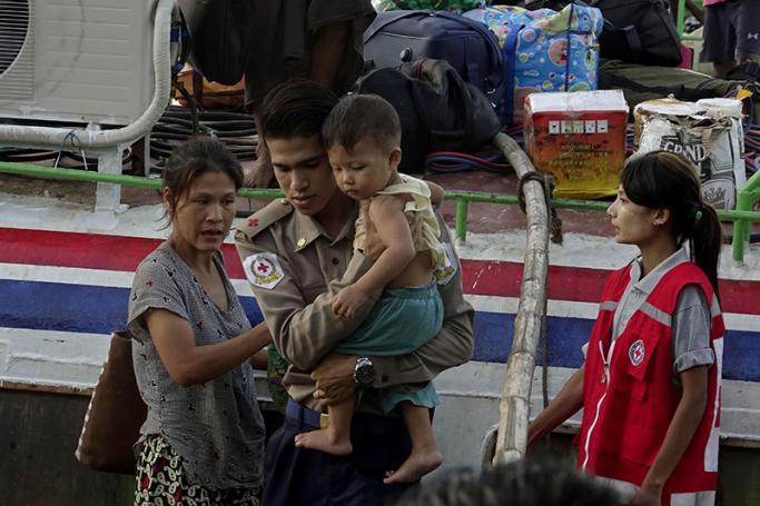 A Red Cross member carries a child as he helps a displaced Rakhine ethnic woman from Maungdaw township at the Sittwe port, Sittwe, Rakhine State, western Myanmar, 28 August 2017. Photo: Nyunt Win/EPA
