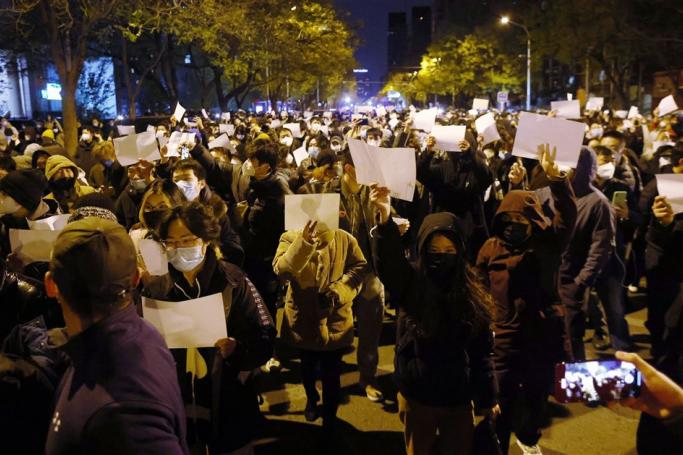 Protesters hold blank white pieces of paper during a protest triggered by a fire in Urumqi that killed 10 people in Beijing, China, 27 November 2022. Photo: EPA