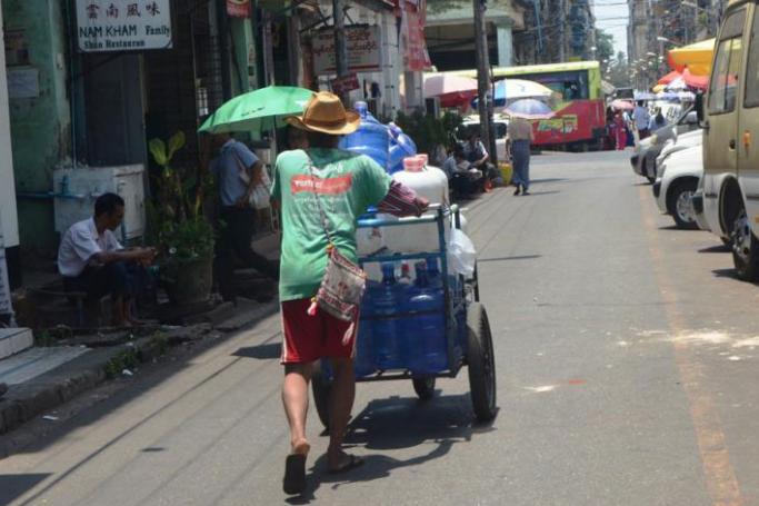 A man pushes a cart loaded with water bottles on a street in Yangon. Photo: Htet Hkaung Linn/Myanmar Now
