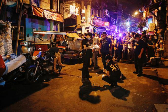 Filipino police investigators examine a crime scene after an alleged drug user was shot dead by unidentified men in Manila, Philippines, 24 September 2016. Photo: EPA
