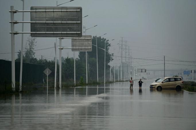 Two men walk down a flooded street following heavy rains which caused flooding and claimed the lives of at least 33 people earlier in the week, in the city of Zhengzhou in China's Henan province on July 23, 2021. Photo: AFP