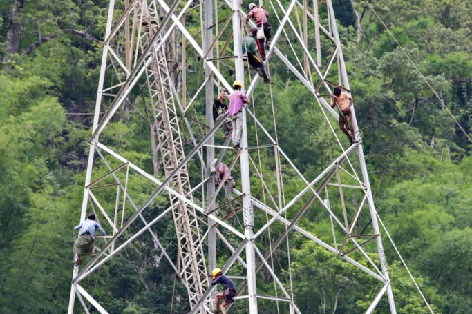 Myanmar workers with cables being attached to a newly built electric pylon on the hill at Kengtung district in Shan State, Myanmar, 24 June 2019. Myanmar government has announced the increase of the electricity rates (which will cost at least double to a normal household family) as the first time in last five years amid severely blackouts in Yangon and across the country. Photo: Lynn Bo Bo/EPA