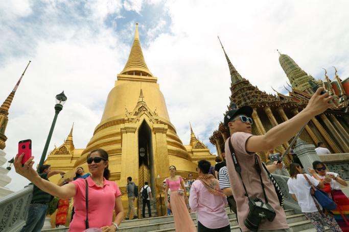 Foreign tourists take selfies with their mobile phone cameras as they are sightseeing the Emerald Buddha Temple inside the Grand Palace in Bangkok, Thailand. Photo: EPA