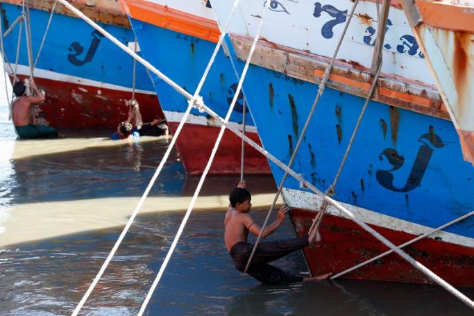 Migrant fishermen from Myanmar clean Thai fishing boats docked after fishing operations were stopped at a port in Samut Sakhon province, Thailand, 01 July 2015. Photo: Rungroj Yongrit/EPA
