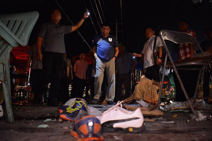 A handout picture dated and released on 03 September 2016 by the Presidential Photographers Dividion (PPD) shows Filipino President Rodrigo Duterte (C) inspecting an evidence at the site of an explosion at a night market in Davao city, Philippines. Photo: EPA
