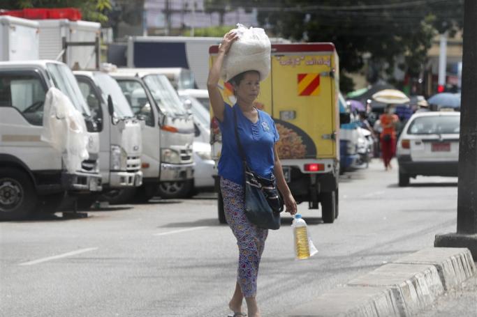 A woman carries rice and cooking oil in Yangon, Myanmar. Photo: EPA