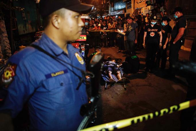 Filipino police investigators examine the body of an alleged drug user was shot dead by unidentified men in Manila, Philippines, 24 September 2016. Photo: Mark R. Cristino/EPA
