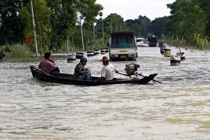 A boat loaded with passengers circumnavigates a flooded road as vehicles are seen in the background, near Dar Ka township of Ayeyarwaddy Region, Myanmar, 12 August 2015. Photo: Lynn Bo Bo/EPA
