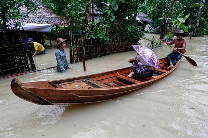 Myanmar is prone to the downsides of natural and man-made climate change. A man rows a boat with passenger as they pass through a flooded road at Kyein Chaung village of Kangyee Daunk township in Ayeyarwady Region, Myanmar, 12 August 2016. Photo: Lynn Bo Bo/EPA
