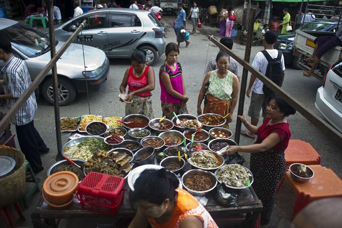 Vendors sell food at their stall on a street in Yangon. Photo: Ye Aung Thu/AFP
