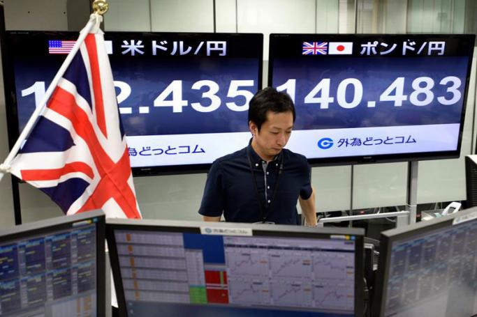 A monitor (R) displays the current exchange rate of the Japanese yen against the British Pound as a trader works at a foreign exchange brokerage in Tokyo, Japan, 24 June 2016. Photo: Franck Robichon/EPA
