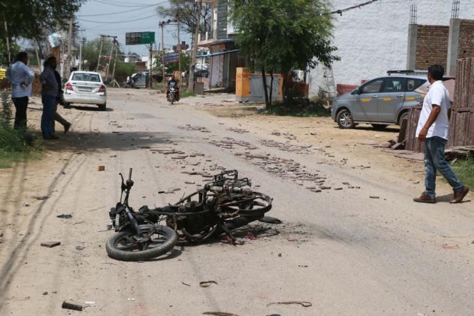 A man walks past a burnt motorcycle in the aftermath of riots in Nuh, Haryana state, India, 01 August 2023. Photo: EPA