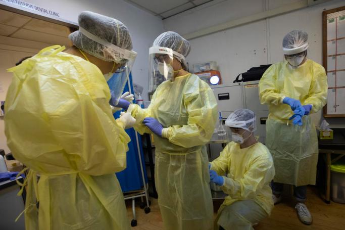 Volunteer medical personnel put on their personal protection equipment (PPE) at a Healthserve clinic in Singapore, 18 August 2020. Photo: EPA