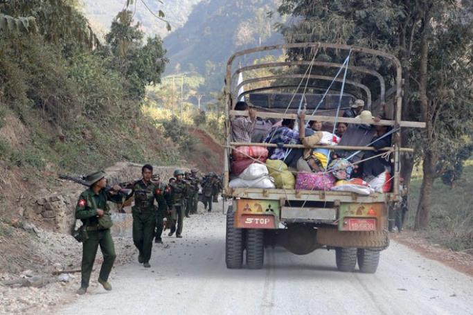 A rescue truck loaded with fleeing civilians passes military troops near the Kokang capital Laukkai, northern Shan State, Myanmar, February 17, 2015. Photo: Lynn Bo Bo/EPA
