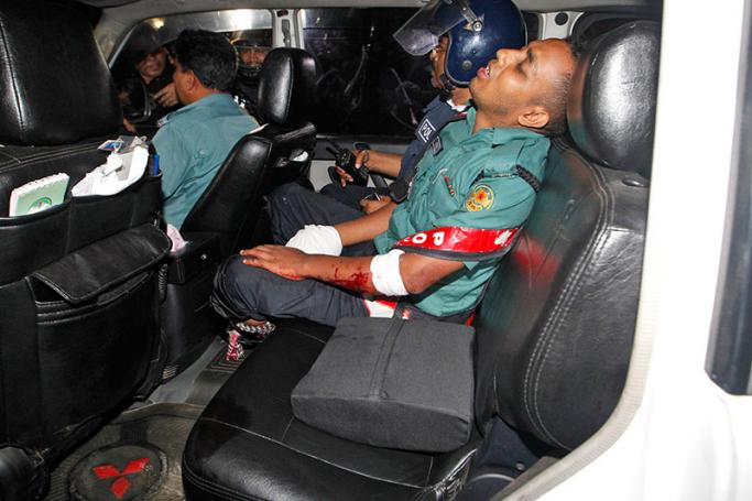 An injured police officer sits in a car after suffering wounds from a crude bomb blasted by suspected criminals at a Spanish restaurant in Dhaka, Bangladesh, 1 July 2016, prior to commandoes storming the building.Photo: EPA
