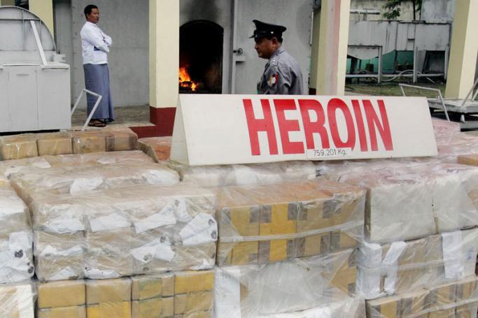 A Myanmar security official stands next to stacks of seized Heroin to be burned in a incinerator at a ceremony in Yangon. Photo: AFP