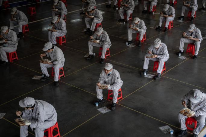 Workers have lunch while sitting 1.5 meters away from others at the joint-venture Dongfeng Honda in Wuhan, Hubei province, China, 23 March 2020. Photo: EPA