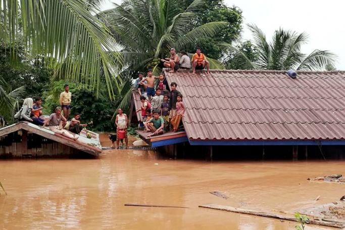 Lao villagers are seen stranded on rooftops of houses to evacuate from floodwaters after the Xe Pian Xe Nam Noy dam collapsed, in a village near Attapeu province, Laos, 24 July 2018. Photo: ABC Laos News/EPA
