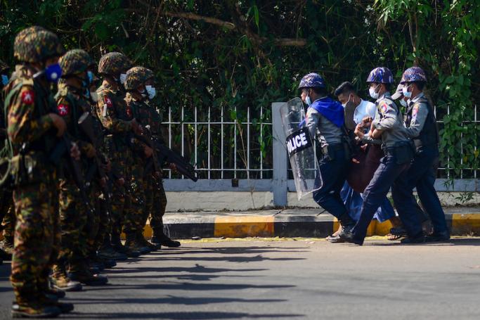 Police arrest a protester as armed soldiers stand guard during a demonstration against the military coup in Mawlamyine in Mon State on February 12, 2021. Photo: AFP