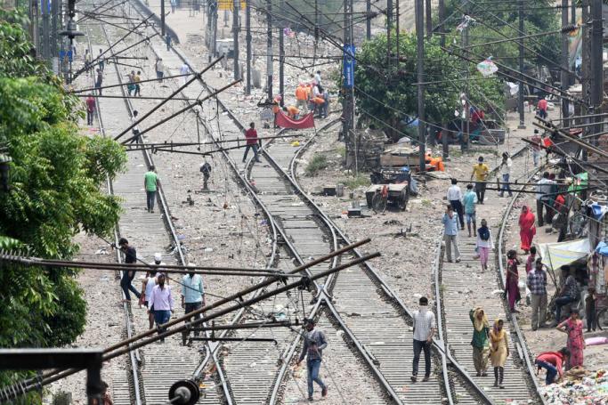Indian people walk on railway tracks outside their homes during an extended lockdown, in New Delhi, India, 11 May 2020. Photo: EPA