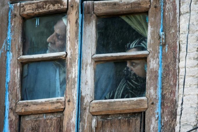 Kashmiri residents watch from their window near the site of a gun battle between suspected militants and Indian government forces on May 19, 2020 in the main city of Srinagar (AFP/File Photo/ Tauseef MUSTAFA)