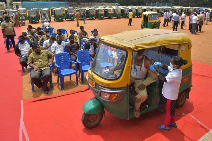 An auto rickshaw driver receives a jab of CoviShield vaccine against the Covid-19 coronavirus during a free vaccination drive for the drivers in Bangalore on August 25, 2021. Manjunath Kiran / AFP