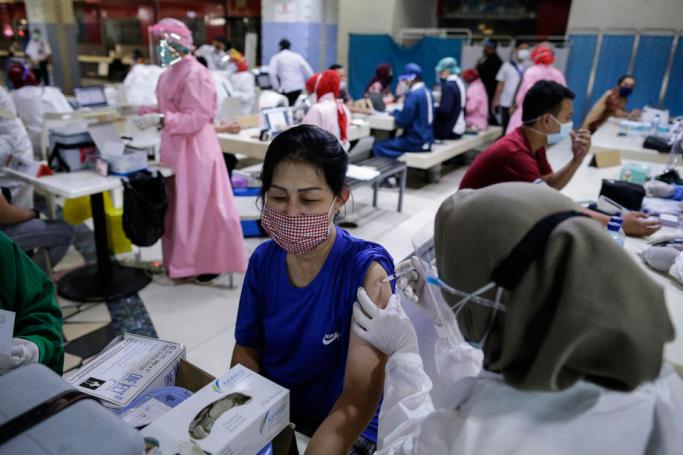 99 A healthcare worker injects a dose of Sinovac COVID-19 vaccine during a mass vaccination drive for vendors and shop keepers at Tanah Abang textile market in Jakarta, Indonesia, 17 February 2021. Photo: EPA