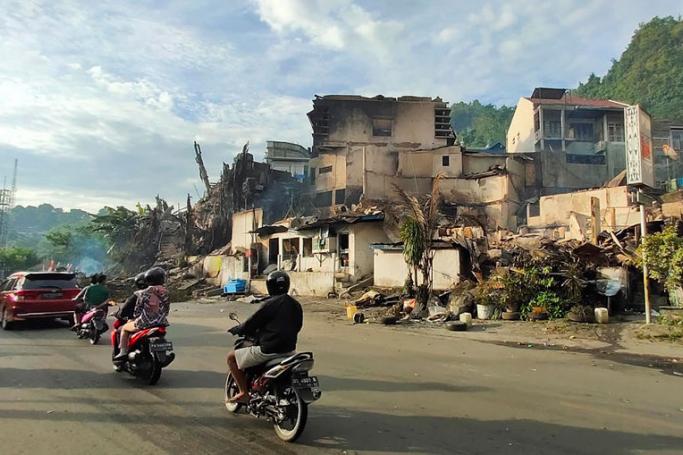 Motorists ride pass a burnt out building a day after it was torched by protesters during a violent rally in Jayapura, Papua province, Indonesia, 30 August 2019. Photo: EPA