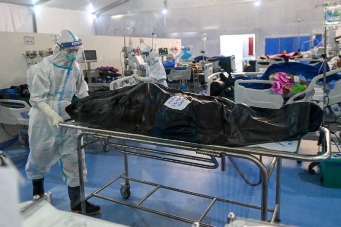 This photo taken on December 19, 2020 shows healthcare workers wearing personal protective equipment (PPE) as they prepare to transfer the body of a person who died from the Covid-19 coronavirus at the Ayeyarwady Covid Center at the Thuwana football stadium in Yangon, amid the ongoing Covid-19 coronavirus pandemic.  Photo: AFP