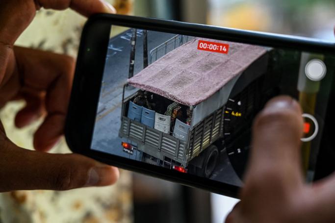 A person holds a mobile phone showing a video of soldiers looking out from a truck in Yangon. Photo: AFP