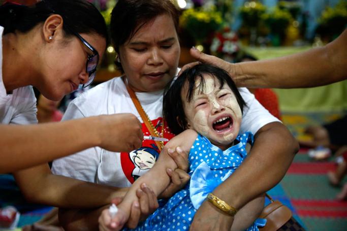 A girl reacts as medical staff injects the Japanese encephalitis vaccine to his arm, Yangon, Myanmar, 12 December 2017. Photo: Lynn Bo Bo/EPA-EFE
