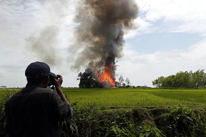 Journalist take photos of a burning house at the Gawdu Thara village in Maungdaw township, Rakhine State, western Myanmar, 07 September 2017. Photo: Nyein Chan Naing/EPA

