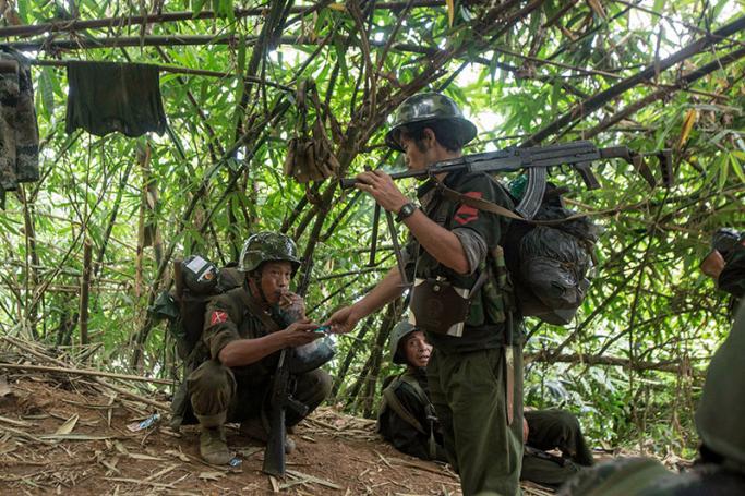 In this photograph taken October 14, 2016, armed rebels belonging to the Kachin Independence Army (KIA) ethnic group take a cigarette break as they move towards the frontline near Laiza in Kachin state. Photo: Hkun Lat/AFP

