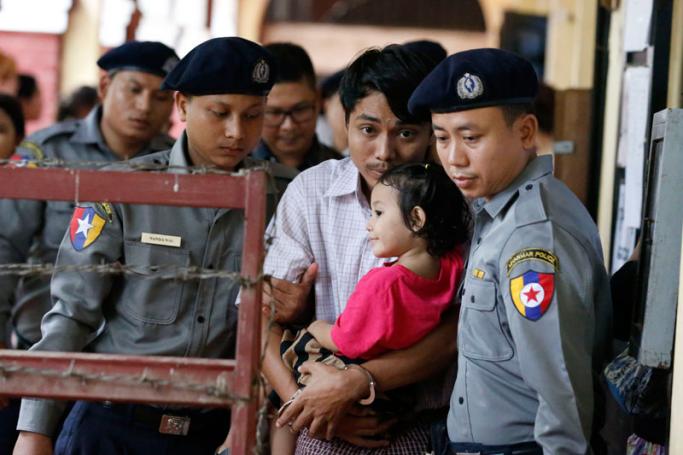 Detained Reuters journalist Kyaw Soe Oo (C) carries his daughter though the court grounds during a break in his trial in Yangon, Myanmar, 17 July 2018. Photo: Nyein Chan Naing/EPA
