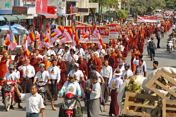 (File) Buddhist monks and lay people hold placards and Buddhist flags as they march during a demonstration in Mandalay, Myanmar, 30 October 2014. Photo: EPA
