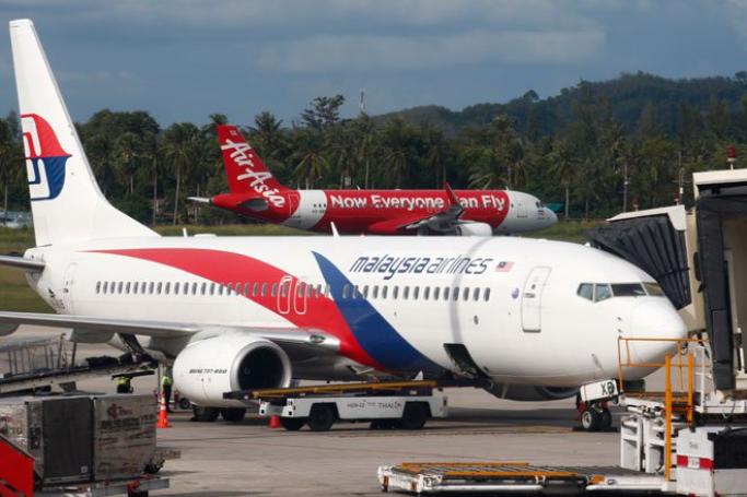 An AirAsia plane about to take off behind a boarding Malaysia Airlines plane on the resort island of Phuket, southern Thailand, November 2, 2014. Photo: Barbara Walton/EPA
