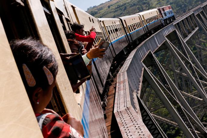 Passengers look out of window and take photographs with mobile phone as Mandalay-Lashio transport train passes over Gokteik viaduct in Shan State, Myanmar. Photo: Lynn Bo Bo/EPA